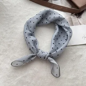 Polka dot light blue cotton neck scarf tied in a bow knot on soft plush background