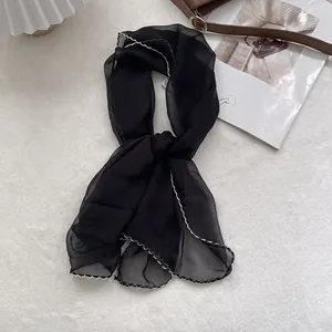 Detail of black chiffon neckerchief with decorative wavy embroidery on scalloped edges