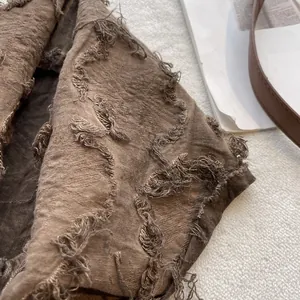 Detailed macro view of the dark brown cotton linen scarf with vintage frayed edge texture