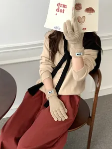 Detailansicht der beige gestrickten Fingerhandschuhe mit hellblauem Label am Bündchen