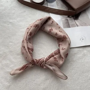 Close-up of knotted floral cotton linen scarf on white fleece with lifestyle accessories