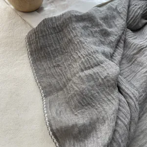 Close-up of dark grey wrinkled cotton linen scarf featuring delicate overlock stitching
