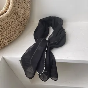 Detail showing elegant black lightweight silk scarf with white wavy embroidered edges