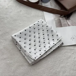 Detailed view of white polka dot cotton scarf with premium stitching on soft background