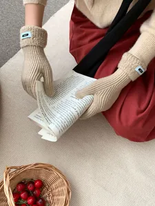 Detail der beigen Strickhandschuhe mit Rippstruktur und ERET-Webetikett am Handgelenk