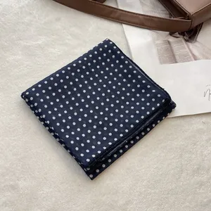 Detail of navy blue polka dot cotton scarf texture on a soft white plush surface