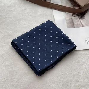 Detail of dark blue polka dot cotton scarf with fine stitched edges on white faux fur