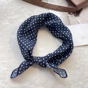 Close-up of a navy blue polka dot cotton neck scarf tied in a stylish knot on a white rug