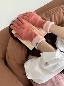 Detail von rosa Strickhandschuhen mit flauschigen Teddy-Fleece-Bündchen und blauem Label