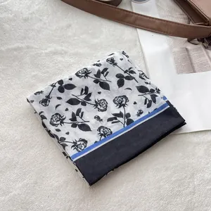 Detail of rose floral print cotton bandana with blue stripe and black border on plush rug