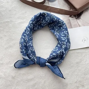 Blue vintage cotton linen headscarf with white floral print arranged with lifestyle props