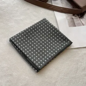 Macro detail of dark grey polka dot cotton neckerchief with neat rolled edge stitching