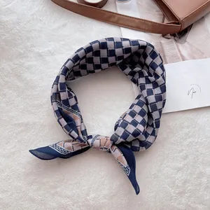 Détail d'un foulard en coton et lin à carreaux bleu marine et beige sur fond blanc doux