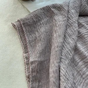 Close-up of pleated cotton-linen scarf fabric with premium woven edge stitching