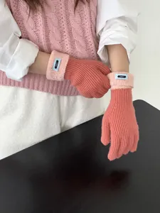 Details von korallenrosa Strickhandschuhen mit Plüschbündchen und Markenetikett