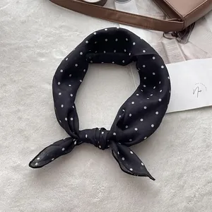 Macro shot of polka dot silk scarf tied in a bow on a white plush rug for styling