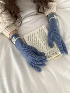 Detailed view of blue knitted touchscreen gloves with white stripes on an open book