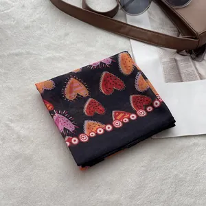 Detailed top view of a black linen headscarf with heart prints and fashion accessories