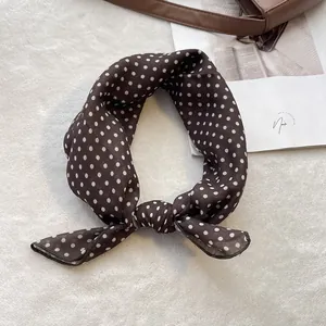 Close-up of retro brown polka dot silk scarf tied on a stylish leather handbag strap