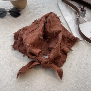 Detailed macro view of the rust red cotton-linen scarf with retro frayed edges