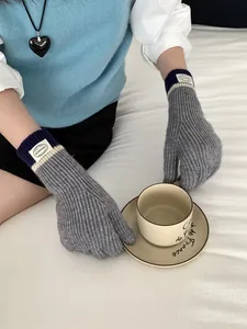 Detail of knitted touchscreen gloves with ribbed cuffs and branding label on the wrist