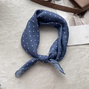 Detailed close-up of navy blue polka dot cotton neckerchief on a soft textured background