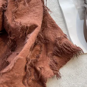 Detail of beige tie-dye cotton linen scarf showing frayed edges and wrinkled texture