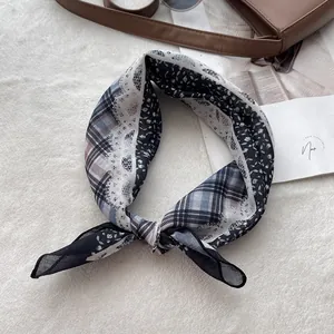 Detail of blue and black cotton floral paisley scarf tied on a stylish leather bag