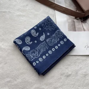 Detailed view of dark blue paisley cotton bandana with white floral pattern on textured blanket