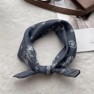 Detail of dark grey paisley cotton linen scarf tied on a white faux fur background