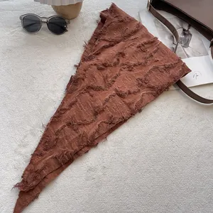 Detail of a brown cotton linen neck scarf featuring frayed edges and textured fabric finish