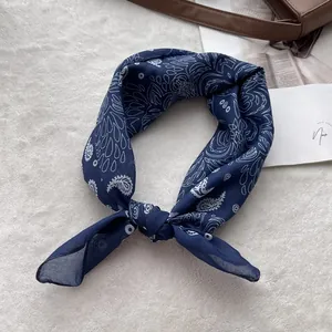 Detail of dark blue paisley cotton linen headscarf tied in a knot on soft texture