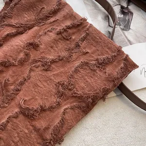 Close-up of brown linen scarf showing textured fringe and intricate tufted details
