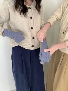 Close-up of pink and blue cable knit wool gloves featuring ribbed cuffs and leather tags