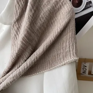 Detail of brown pleated cotton linen scarf with white wave lace trim on decorative edges