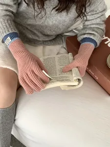Pink knit touch screen gloves with blue ribbed cuffs shown while reading a book