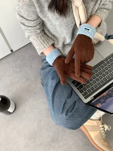 Detail von grob gestrickten braunen Handschuhen mit hellblauen Plüschbündchen