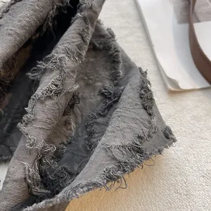 Close-up of distressed dark gray cotton scarf with frayed edges and vintage texture