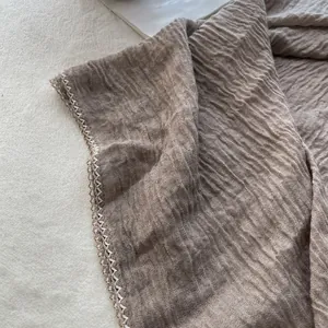 Detail of taupe pleated cotton linen scarf with elegant cream crochet lace edge