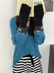 Detail der schwarzen Strickhandschuhe mit grauen Rollbündchen und blauem Akzent-Etikett