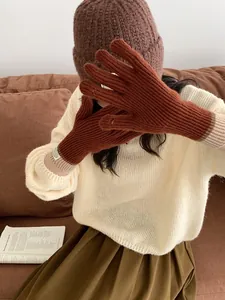 Detail of caramel knit gloves featuring touchscreen fingers and striped ribbed cuffs
