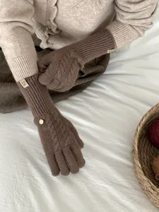 Detail of dark brown cable knit wool gloves with ribbed cuffs and metallic accent