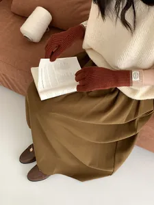 Close-up of caramel rib-knit touchscreen gloves with vintage brand label detail