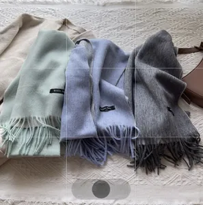 Detailed view of 100% wool scarves in mint green, light blue and grey with tassel edges