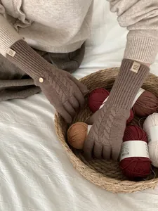 Close-up of dark brown cable knit wool gloves featuring ribbed cuffs and woven texture