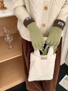 Detailansicht olivgrüner Strickhandschuhe mit braunen Plüschbündchen und Webetikett