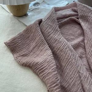Detail of light pink crinkled cotton linen scarf showing soft texture and fine stitching