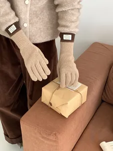 Detail of color-block knit touchscreen gloves with beige body and dark brown ribbed cuffs