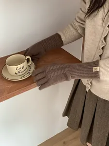 Detail of wool knit gloves in dark brown featuring vintage cable pattern and ribbed cuffs