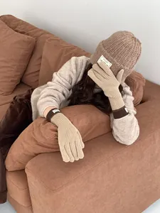 Detail of warm knitted hat and long gloves set with decorative fabric labels in camel beige